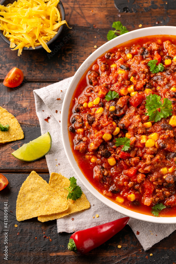 Poster chilli con carne with tortilla chips and cheese in white bowl. mexican food.