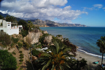 Fototapeta premium Scenic shot of the coastline at Nerja with palm trees , mountains , blue sky and seaside