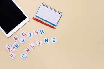 Concept of studying English online, internet courses, distance learning of foreign language. Horizontal banner with tablet, notebook, pen, inscription learn English. Beige background. Copy space. 