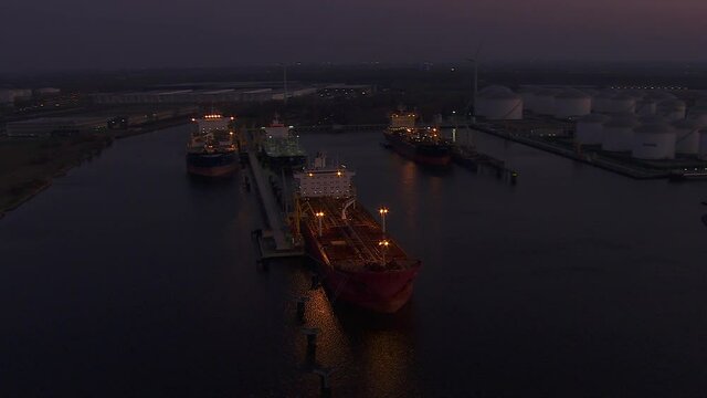 Sun setting over Antwerp industrial harbor with some oil and gas ships in night modus operandi