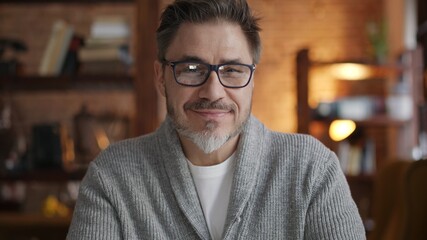 Happy bearded older man at home wearing glasses looking at camera, smiling. Portrait of mature age,...