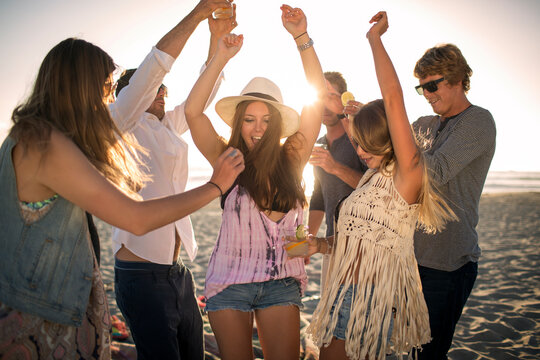Cheerful friends dancing on beach