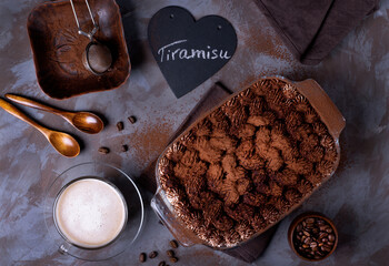 Tiramisu cake sprinkled with cocoa powder and cup of coffee. Italian dessert. Top view
