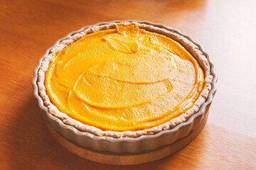 Pumpkin pie, orange cake in a baking dish on a wooden table