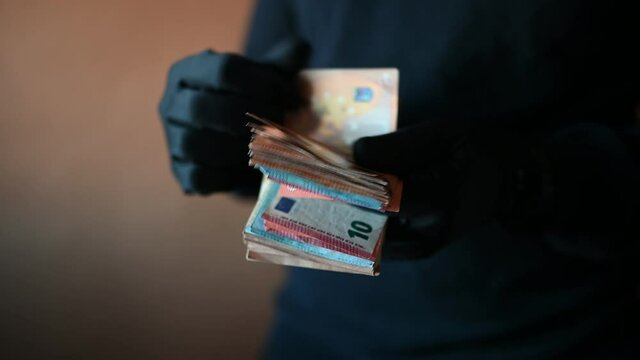 Closeup of hands with black gloves counting a handful of euro bills