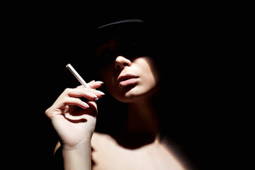 Fototapeta premium Beautiful woman in a hat and with a cigarette