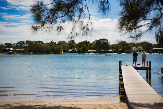 Rear view of senior man and woman standing on pier over lake during sunny day