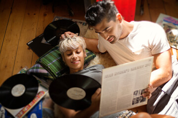 Overhead view of couple looking at vinyl records while lying on floor