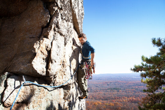 Side view of man rock climbing against clear sky