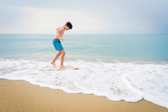 Young teen surfing on seashore in sunny day