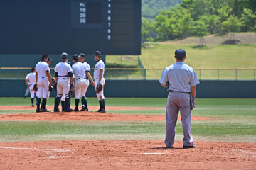 高校野球の試合でマウンドに集まる選手と審判