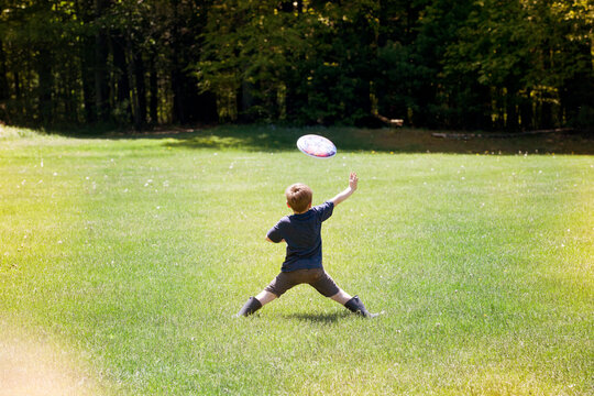 Rear view of boy throwing frisbee at park