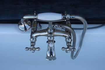 Close-up view of the decorative chrome and porcelain  faucet for an antique bathtub