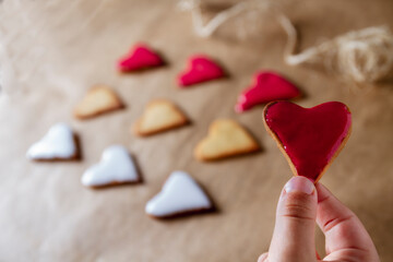 child's hands showing a heart-shaped cookie decorated with red pastry