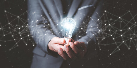 Businessman holding glowing lightbulb with drawing brain and connection line, creative thinking...