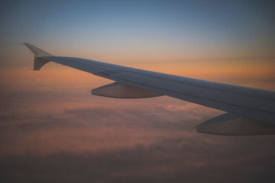 The wing of an airplane in an orange sunset sky