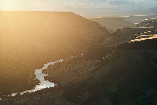 River Winding Through Desert Canyon at Sunset with Sun Flare