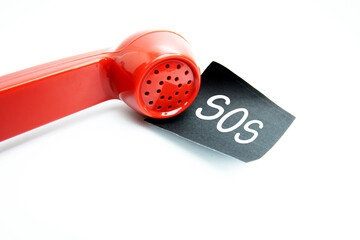 Getting a call that is an SOS, A retro red phone with black sticky note on a desk with text SOS