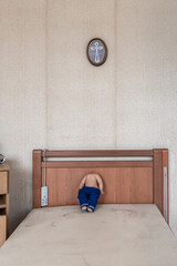 Headless doll on a bed and a crucifix above it