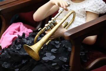 A girl schoolgirl of elementary grades with a musical trumpet in her hands in a white blouse and...