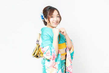 白背景の前に立って、パンチのジェスチャーをする振袖を着た女性