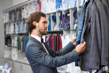 Man with curly hair picking up suits.