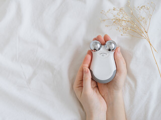 Microcurrent concept. Face massager with micro currents for home use and skincare on white bed....