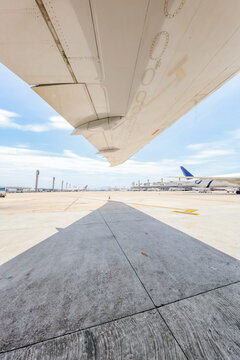 Under wing view of jet airliner showing tarmac