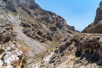 Aerial view of a narrow, barren gorge with lush green foliage in the bottom