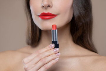 Lower part of womans face and red lipstick in hand