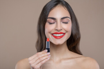 Woman with closed eyes with lipstick in hand