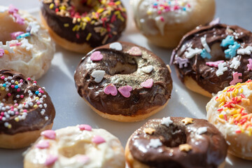 Leckere Donuts mit Schokolade un bunten Streusel überzogen. Herzen zum Valentinstag und Geburtstag. Süßes für Verliebte. 