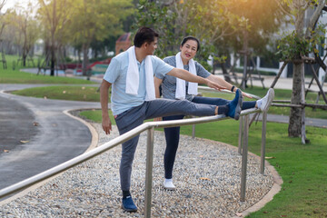 Fototapeta premium senior couple finished their run, had a towel over their necks and stretched their legs on a bra in the park in the morning.