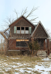 Abandoned wood paneled Tudor home in Detroit's Franklin Park neighborhood in winter