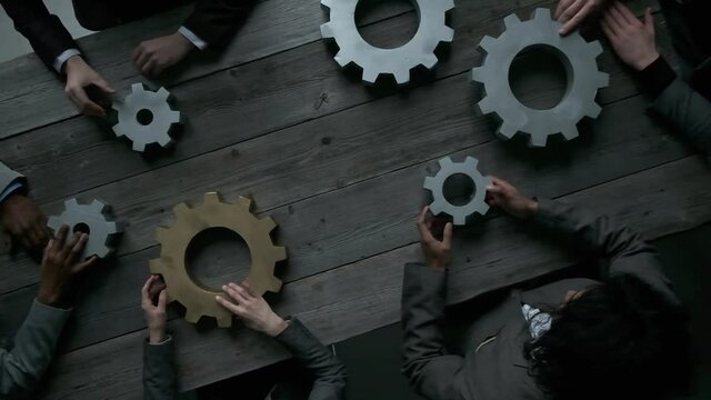 Business people connect gear together at meeting table, success cooperation teamwork concept