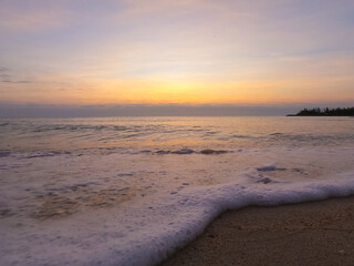 Landscape view close up wave and bubbles on the beach with light effects in sunrise time