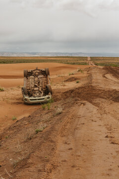 upside down car that has flipped on a muddy dirt road in utah desert