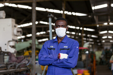 Portrait of black male engineer wearing protective medical face mask at work in the industry factory. African American male worker wearing protective medical face mask for health in the factory