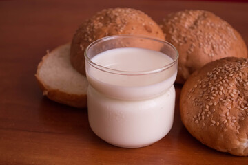 Milk in a glass and buns on a dark wooden background. Selective focus.Rustic style.