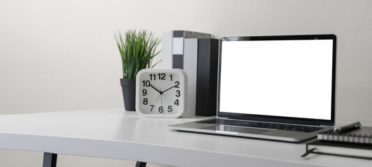 Modern contemporary workspace with blank screen laptop computer with office supplies and stationery on office desk on white background for copy space. Home office workplace concept.