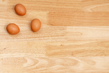 Three eggs on the upper left corner of the wooden table