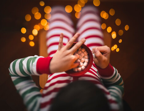 Overhead shot of child taking marshmallow out of cup of hot cocoa.