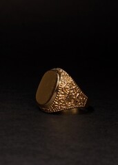 Mens gold signet ring on a black background.