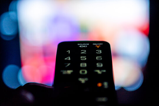 Close-up of a person changing the television with the remote control in quarantine period