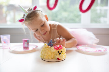 cute girl with unicorn headband tasting birthday cake