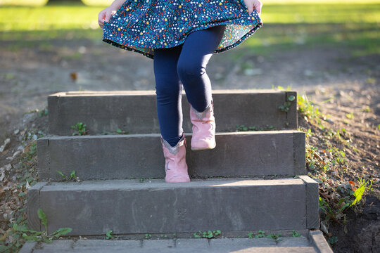bottom half view of little girl walking down steps holding skirt