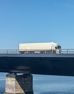 Truck driving on bridge over water.
