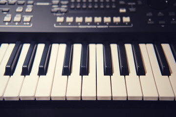 Fototapeta premium Black synthesizer with white keys, modern electronic piano with sliders and buttons for recording music