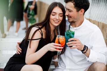 couple seating on the beach bar and drink cocktails. couple drink cocktails