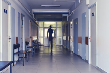 Blurred silhouette of a man passing away through the hospital hallway. The concept of problems of...